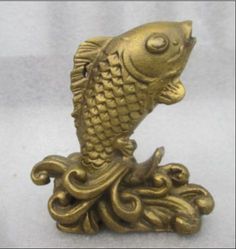 a gold fish statue sitting on top of a white surface