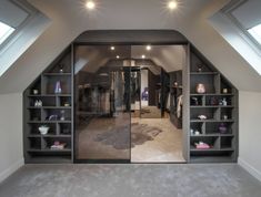 an attic bedroom with open closets and shelves filled with clothing on top of carpeted flooring