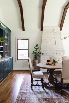 a dining room table with chairs and a potted plant in the corner next to it