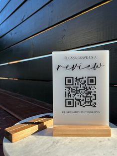 a table with a qr - code on it next to a wooden block that says please leave us a review