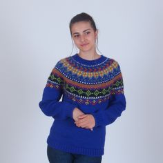 a woman wearing a blue sweater with multicolored fair - stitching on it