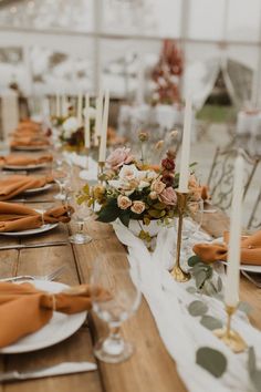 the table is set with orange napkins and place settings for an elegant dinner party