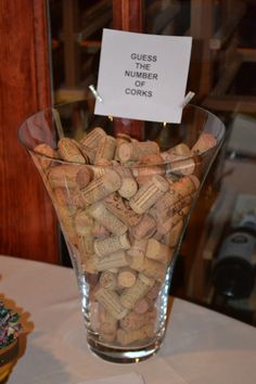 a glass vase filled with lots of corks on top of a white table cloth