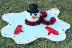 a snowman is sitting on top of a white sign with red mittens and a black hat