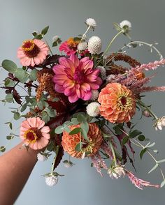 a bouquet of flowers is being held up by someone's arm with the other hand