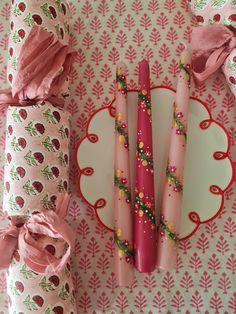 four pink candles sitting on top of a plate next to rolls of paper and napkins