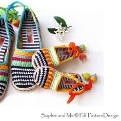 crocheted slippers with tassels and flowers on white surface next to plant