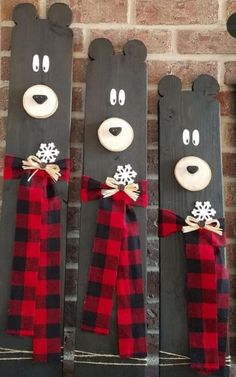 three black bears with red and black plaid scarfs hanging from the side of a brick wall