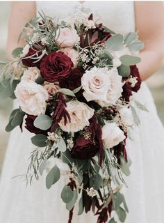 a bridal holding a bouquet of red and white flowers with greenery on it