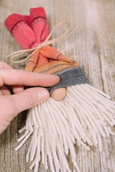 someone is making a small doll out of yarn and fabric with two hands on the table