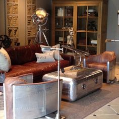 a living room filled with lots of leather furniture and decorating items on top of a rug