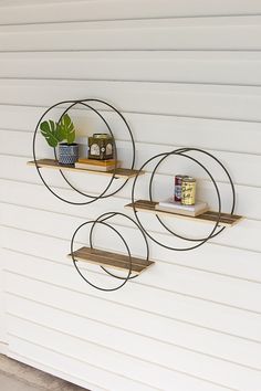 three circular metal shelves on the side of a white building with a potted plant