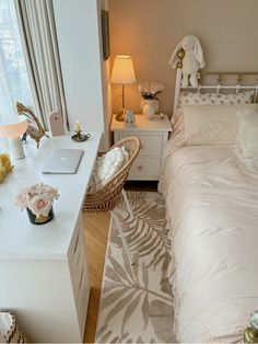 a white bed sitting next to a desk with a laptop computer on top of it