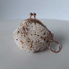 a white beaded purse sitting on top of a table next to a gold ring