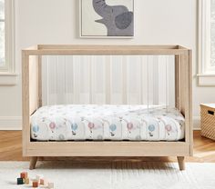 a baby crib in the corner of a room with wooden floors and white walls