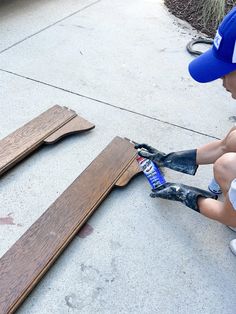 a young boy sitting on the ground working on some wood