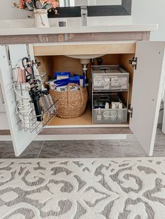 an open cabinet in a bathroom with baskets and other items on the shelf below it