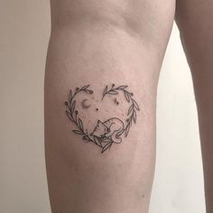 a heart shaped tattoo with a cat sleeping on it's back legs and leaves