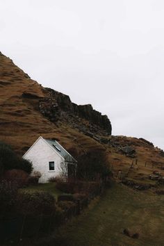 a small white house sitting on the side of a hill