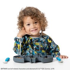 a little boy that is sitting in front of a table with some containers on it