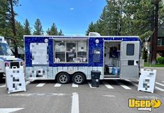 a blue and white food truck parked on the side of a road next to trees