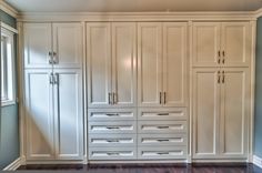 a large white closet with many drawers and doors on the wall next to a window