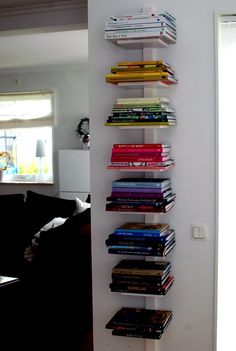 a book shelf filled with lots of books on top of a white wall next to a doorway