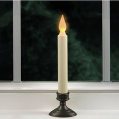 a lit candle sitting on top of a window sill