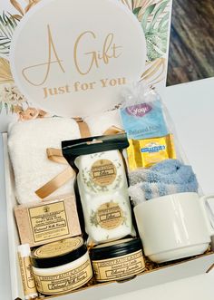 a gift box filled with personal care items and a coffee mug next to it on top of a table