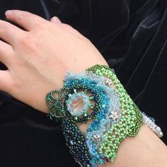 a woman's hand wearing a green and blue beaded bracelet on her wrist