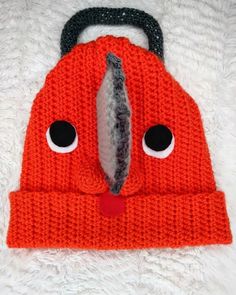 an orange knitted hat with eyes and a black handle