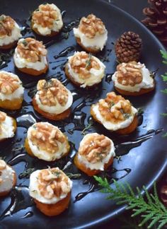 a black plate topped with mini cupcakes covered in frosting and toppings