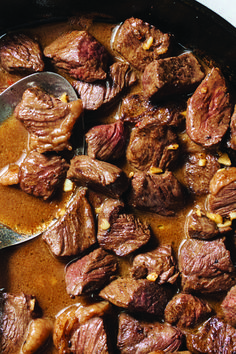 a pan filled with meat and sauce on top of a stove