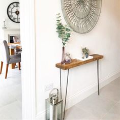 a table with some plants on it in front of a wall clock and other decorations