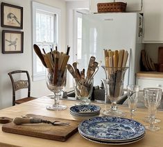 a kitchen table with plates, glasses and utensils