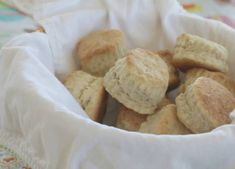 a basket filled with biscuits sitting on top of a table next to a white cloth