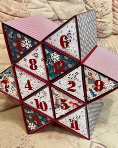 an origami christmas decoration with numbers and snowflakes on the sides, sitting on a table