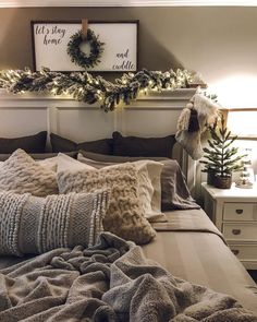 a bed topped with lots of pillows next to a christmas wreath on top of a wall