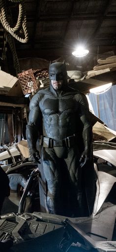 the dark knight batman is standing in his garage