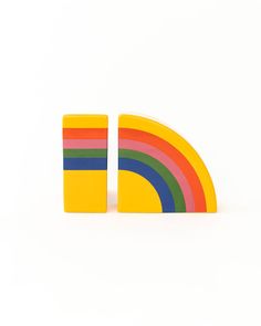 a pair of colorful wooden blocks sitting next to each other on a white surface with a rainbow in the middle