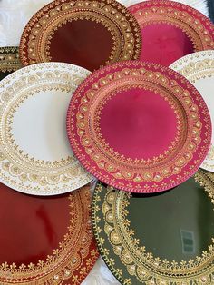 several plates with gold and red designs on them are arranged in a row, one is empty