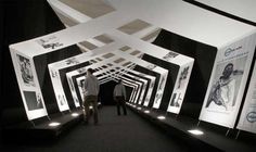 two men are walking through a tunnel made of black and white paper with images on it