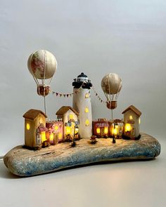 a wooden table topped with hot air balloons and houses covered in paper mache on top of a piece of driftwood