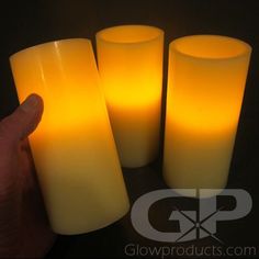 three yellow candles being held in front of each other