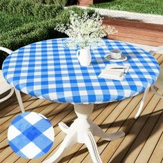 a blue and white checkered table on a wooden deck next to some flowers in a vase