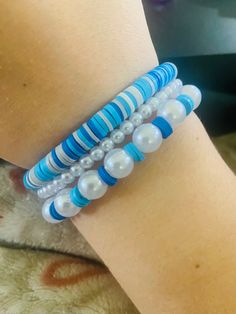 a woman's arm with three bracelets on it, one is blue and the other is white