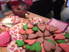 some heart shaped cookies are sitting on plates next to other desserts and candy bars