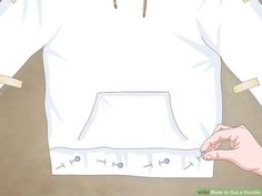 a white shirt with holes on it being held up by someone's hand and wearing a pair of scissors