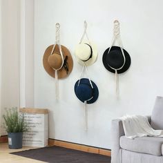 three hats hanging on the wall next to a couch