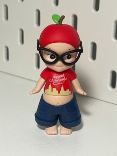 a small figurine wearing glasses and a t - shirt with an apple on it